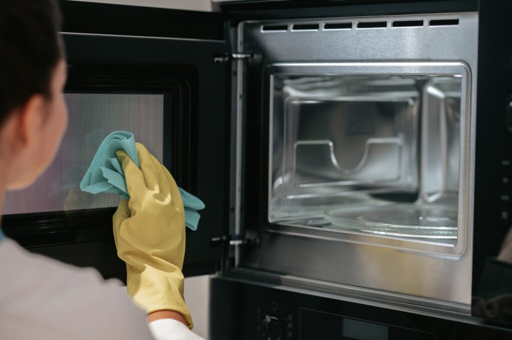 woman-yellow-gloves-cleaning-oven-min